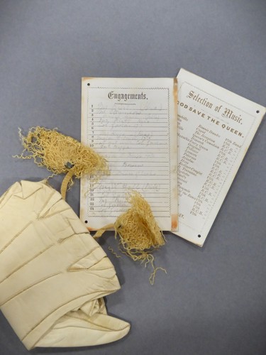 A white leather glove laid across a historic and dance and music card.