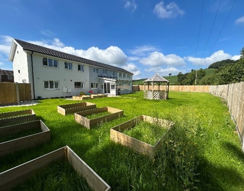 Outside space at Hafan features lawn with a wooden gazebo and raised beds.