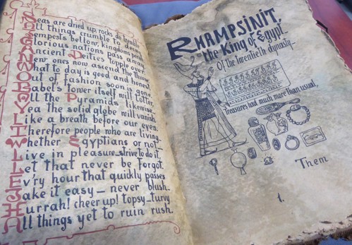 An aged book with rhyming couplets on the one page and depiction of “Rhampsinit the King of Egypt of the Twentieth Dynasty” and his treasures on the other.