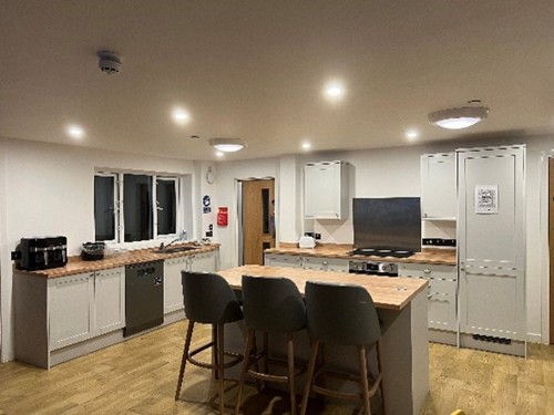 Image of the Kitchen at Hafan, Base units cover the 2 walls with an Island with high chairs in the centre